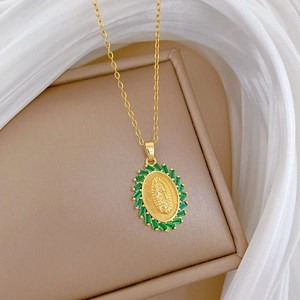 Detailed macro of gold oval medallion with green emerald-cut stones and religious portrait