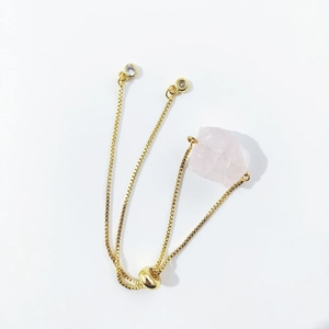 Detail of adjustable gold-tone chain bracelet with natural raw pink crystal and rhinestones