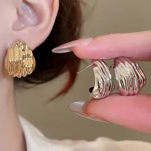 Shell-inspired textured metal stud earrings in gold and silver finish for women