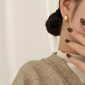 Detail of a minimalist gold geometric hoop earring on a model for an elegant retro look