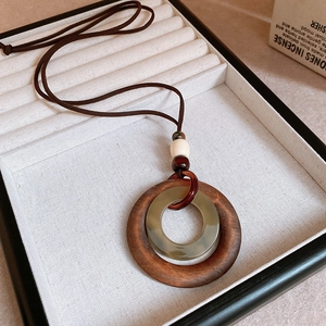Detail of round wooden and resin ring pendant necklace on beige linen jewelry box