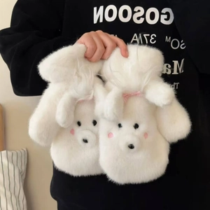 Close-up of white plush dog-shaped mittens with pink bows and cozy faux fur texture