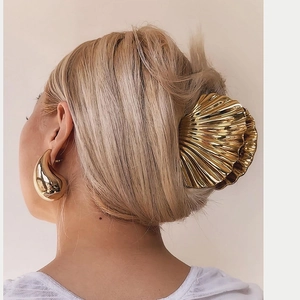 Detailed view of large gold seashell hair claw and matching teardrop earrings set