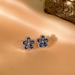 Flower stud earrings with blue teardrop stones and white crystals on champagne satin