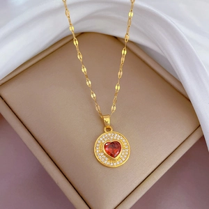 Détail d'un collier en titane doré avec pendentif cœur rouge et oxydes de zirconium