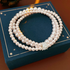 Close-up of multi-layer pearl bracelet with zircon clasp on a blue jewelry box