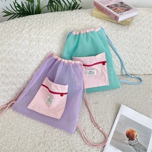 Detail view of purple and green mesh drawstring backpack with pink zipper pocket