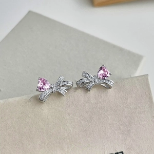 Macro detail of S925 silver bow stud earrings with pink heart shaped zircon stones