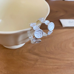 Detailed view of silver post C-shape earrings with hammered metal texture on a ceramic cup