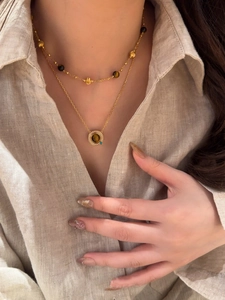 Détail de colliers superposés en plaqué or 18k et œil de tigre sur lin beige