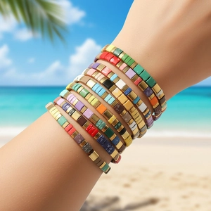 Close-up of stacked colorful Tila bead bracelets on wrist with tropical beach background
