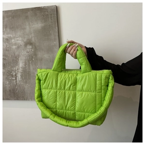 Detail of neon green quilted tote bag with square texture held by model