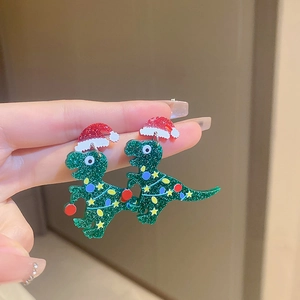 Close-up of green glitter dinosaur earrings with red Christmas hat held in hand