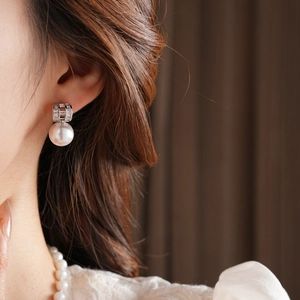 Elegant gold plated pearl drop earrings worn by a model in a luxury close-up shot