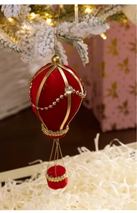 Detail of red velvet Christmas hot air balloon ornament with gold trim on snowy branch