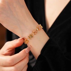 Detailansicht eines Goldarmbands mit Zirkonia-Blumen am Handgelenk eines Models
