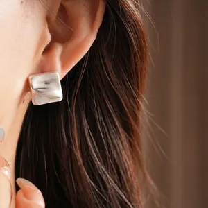 Minimalist silver square earrings with textured crinkle finish on female model