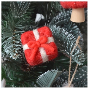 Close-up of a red wool felt gift box ornament with a white bow on a Christmas tree