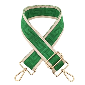 Detail of adjustable green and beige geometric woven shoulder strap with gold metal hooks