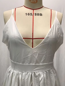 Detail of white V-neck pleated dress with thin straps and elastic high waist design