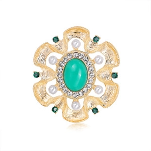 Detail of vintage spider brooch with green oval gemstone, rhinestones and white pearls