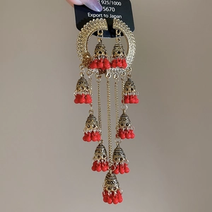 Detail of vintage gold tassel earrings with red beads and intricate hollow carvings