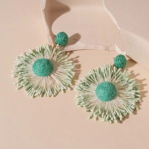 Handmade woven flower earrings with white and green raffia petals for a boho summer look
