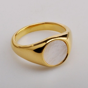 Minimalist gold-plated wide band ring with inlaid white shell on a plain metal surface