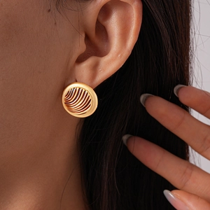 Close-up of a model wearing vintage golden round earrings with wavy textured surface