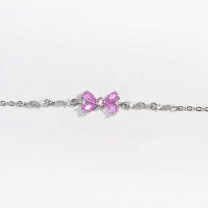 Detail of pink pear-cut zircon butterfly pendant on a silver-tone link chain bracelet