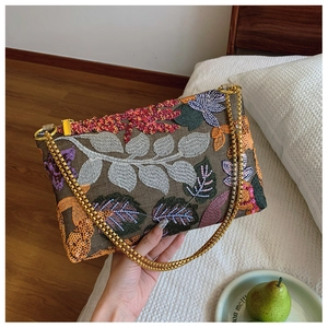 Detailed embroidery and sequins on vintage chain bag with floral leaf patterns
