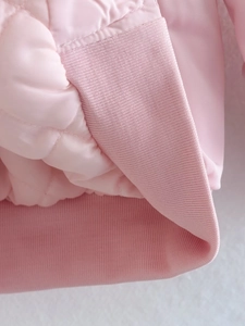 Detail of pink quilted jacket showing ribbed knit cuffs and high-quality fabric texture