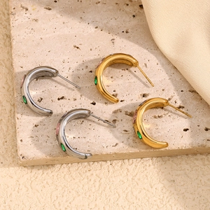 Macro detail of C-shaped 18K gold and silver earrings with colorful zircon stones