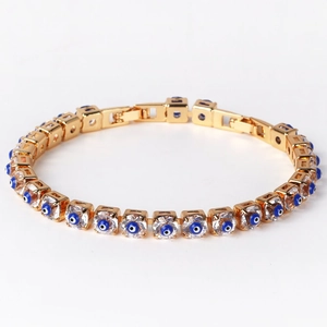 Golden copper chain bracelet with zircon stones and blue evil eye charms on white background