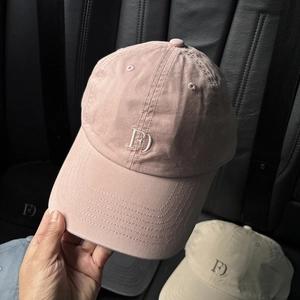 Close-up of FD embroidery and stitching on pink, beige, and blue cotton baseball caps