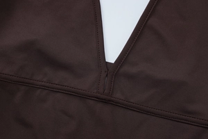 Detailed close-up of a deep brown jumpsuit with a deep V-neck and reinforced stitching