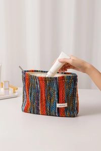 Close-up of bohemian knit makeup bag with multi-color stripes and secure zip closure