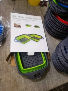 Detailed view of 2-piece green collapsible silicone colander set in open retail packaging
