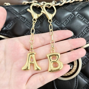 Polished 18k gold plated alphabet A and B keychains on a luxury black bag