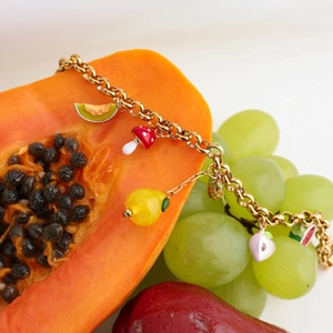 Detail view of a 18K gold-plated chain bracelet featuring colorful fruit enamel charms