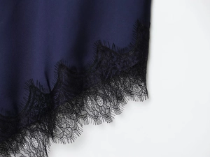 Detailed view of navy blue satin fabric and delicate black eyelash lace trim on dress