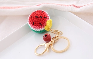 Detailed view of a handmade crochet watermelon keychain with golden chain and red bell