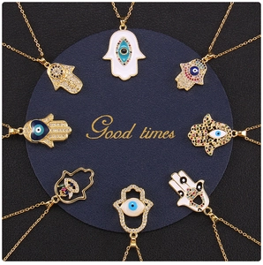 Macro view of gold-plated Hamsa Hand and Evil Eye necklaces with colorful enamel details