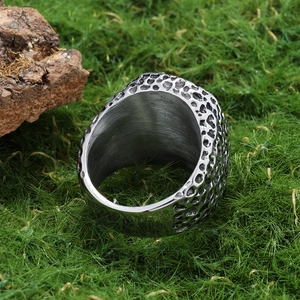 Vintage style metal ring with textured surface and phoenix flower design on green grass