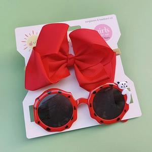 Detail of red bow headband and polka dot sunglasses set with panda icons for girls