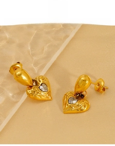 Macro detail of gold-plated titanium heart earrings with hammered texture and zircon