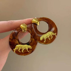 Detailed macro view of amber resin hoop earrings with gold leopard relief charms