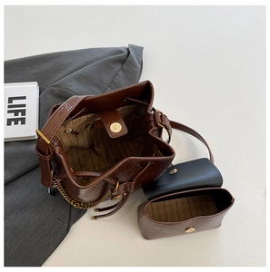 Vue détaillée du sac seau marron vintage avec chaîne dorée et pochette assortie