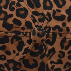 Macro shot of faux suede leopard print fabric with central top button and stitching detail