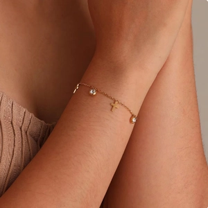 Bracciale a catena in acciaio dorato con ciondoli a croce e zirconi su polso femminile